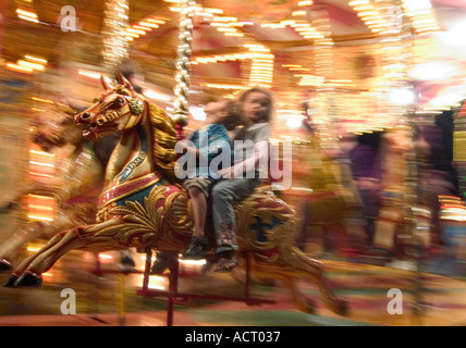 zwei Kinder Jungen und Mädchen auf Festplatz, die Gallopers fahren - verrissen Schuss Stockfoto