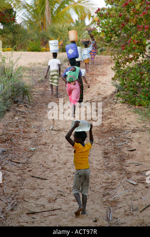 Frauen und Kinder tragen von Wasser aus einer Küste gut in ihre Heimat Mosambik Barra Inhambane Provinz gesammelt Stockfoto