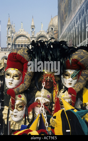 Person umgeben von kunstvollen Masken zum Verkauf am Markusplatz Basilika, Venedig, Italien. Stockfoto