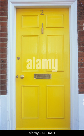 Stilvolle getäfelten Haustür frisch mit weißen Türrahmen und Messing Kricketschläger Klopfer Briefkasten und Anzahl gelb lackiert Stockfoto