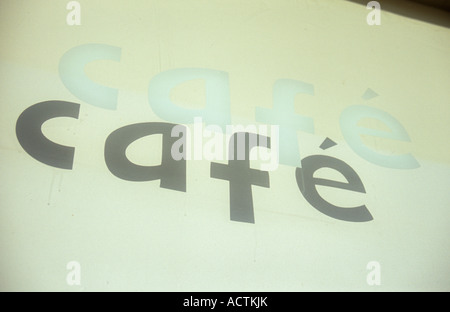 Zeichen gedruckt in weiß auf Fenster besagt Cafe und einen genaue Schatten auf Creme blind hinter gießen, so dass Viewer zuerst Schatten liest Stockfoto