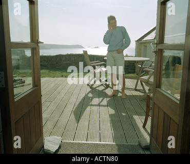 Stehende Figur, Belag, Tisch, Stuhl auf einer Veranda mit Blick auf das Meer am Fistral Strand Newquay, Cornwall. Südwest-England UK Stockfoto