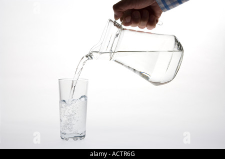 Reines sauberes Wasser aus einem Krug in ein Glas (große Kanne & Longdrinkglas) gegossen Stockfoto