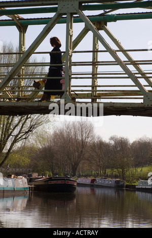 eine Frau, die zu Fuß über eine Eisenbrücke die überspannt den Fluss Lea in Stamford Hill in East London UK Stockfoto