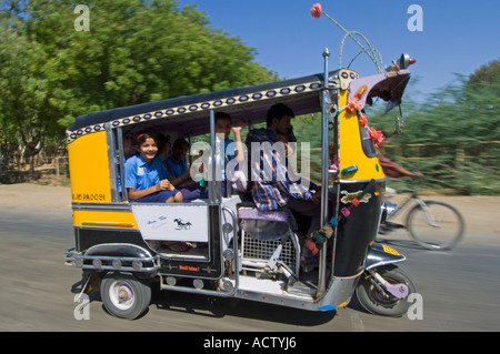 Eine verzierte gelb und schwarz Auto-Rikscha (Tuk Tuk) mit lächelnden Schulkinder mit langsamen Verschlusszeit für Bewegung genommen zu verwischen. Stockfoto