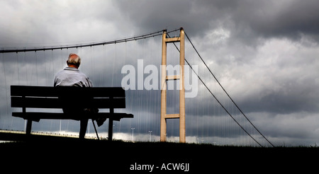 EIN ÄLTERER MANN SITZT AUF EINER BANK, DIE GERADE DER HUMBER-HÄNGEBRÜCKE ZWISCHEN HESSLE UND BARTON AUF HUMBER, JUNI 1981 ERÖFFNET Stockfoto