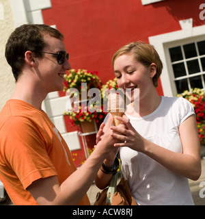 glücklich lächelnd junges Teenager paar jungen und Mädchen ein Eis Kegel Kornett teilen Sommer Aberaeron Ceredigion West Wales, UK Stockfoto