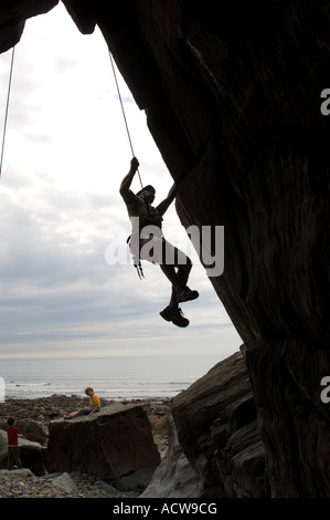 ein junger Mann in Silhouette Klettern am Cae Du Strand Rhosllefain Gwynedd Nord wales UK Stockfoto
