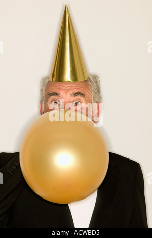 Senior woman einen Luftballon aufblasen Stockfoto