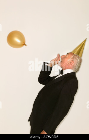 Senior woman einen Luftballon aufblasen Stockfoto