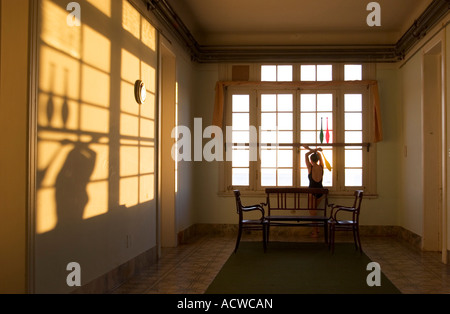 Frau mit Jonglieren Vereine Blick durch ein Fenster mit langen Schatten bei Sonnenuntergang Stockfoto