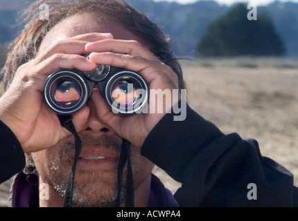 Mann Mittleren Alters An Einem Strand Der Blick Durch Ein Fernglas Mit Seinen Augen Weitgehend Durch Das Fernglas Vergrossert Stockfotografie Alamy