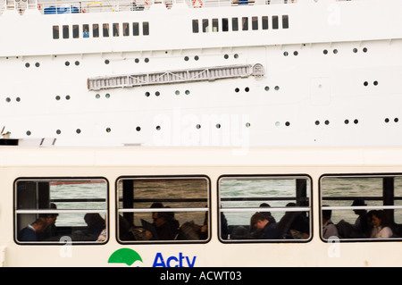 Seiten ein kleines Venedig Bus Fähre voller Pendler und ein großes Kreuzfahrtschiff vorbei an einander Stockfoto