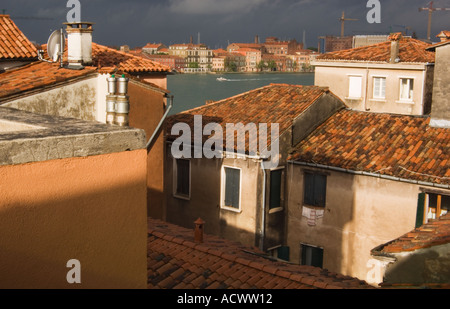 Blick über die Dächer in Venedig Italien mit Terra Cotta Schindeln und Schornsteine Krane Satelliten Gerichte und Kanal im Hintergrund Stockfoto