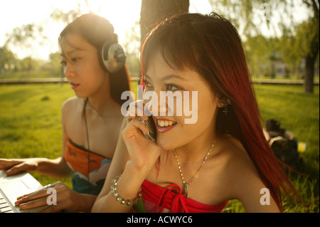Zwei chinesische junge Frauen sitzen auf Rasen Stockfoto