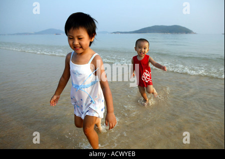 Ein chinesischer Junge und ein chinesisches Mädchen zusammen laufen entlang der Küste Stockfoto