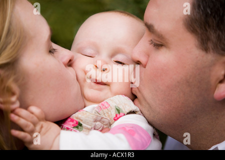 Mit Liebe erstickt.  Porträt einer Mutter und Vater ihr Baby küssen. Stockfoto