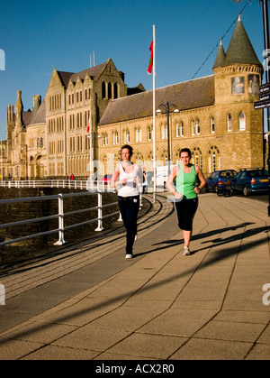 Frauen laufen auf der Promenade Aberystwyth Sommerabend mit der alten Hochschule Universität Gebäude im Hintergrund, Wales UK Stockfoto