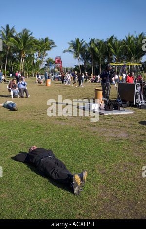 ein Mann gekleidet in schwarzen schlafen auf der Wiese in einem Park in Coconut Grove in Coconut Grove Kunstfestival in Miami, Florida Stockfoto