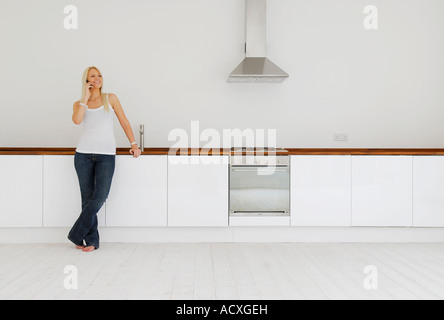 junge Frau am Handy in Küche Stockfoto