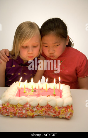 Zwei Mädchen bläst Kerzen aus Geburtstag Kuchen Stockfoto
