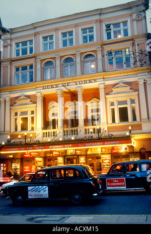 Am frühen Abend beleuchtete Blick auf die Außenfassade des Duke of York Theatre mit schwarzen Taxis im Vordergrund London Stockfoto