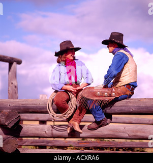 Ein Cowgirl und Cowboy sitzt auf einem Zaun Log in der Cariboo Region British Columbia Kanada Stockfoto