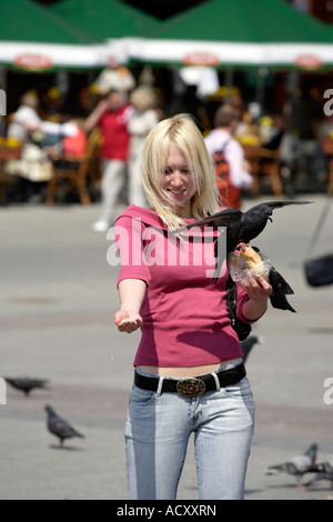 Junge Frau füttern Tauben in den Hauptmarkt in Krakau, Polen Stockfoto