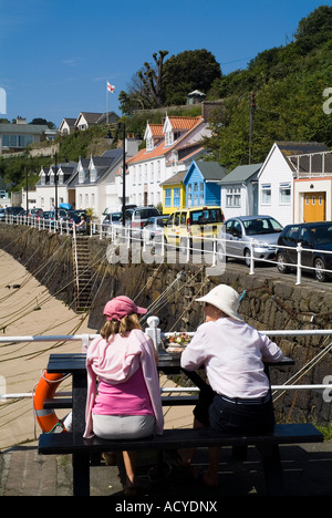 dh Rozel ST MARTIN JERSEY touristischen Frauen sitzen auf Pier Bank Dorf am Wasser gemalt Hütten Häuser Stockfoto