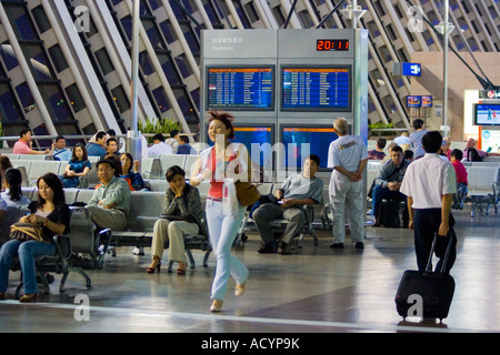 Frau läuft Passagiere warten abgehenden Flug Information Board PVG zum internationalen Flughafen Pudong Shanghai China Stockfoto
