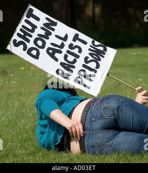 Ein Demonstrator liegt in der Wiese hält einen Banner unter Angabe "heruntergefahren alle rassistischen Gefängnisse". Bild von Jim Holden. Stockfoto