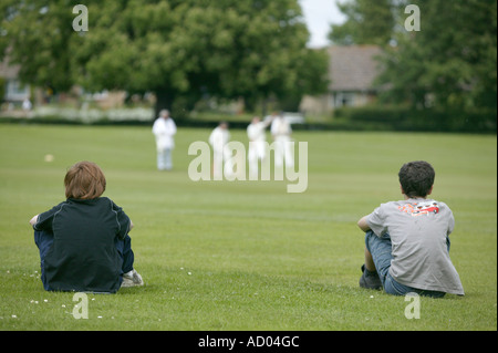 typisches Wochenende ländliches Dorf Szene mit Cricket gespielt auf dem Dorfplatz mit zwei Zuschauer Stockfoto