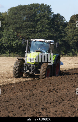 Zugpflug mit Green Claas-Traktoren (Stoppelpflügen, Drehen von Boden und Schlamm, Vorbereitung von Land, Fahren von Landarbeitern) – West Yorkshire, England, GB. Stockfoto