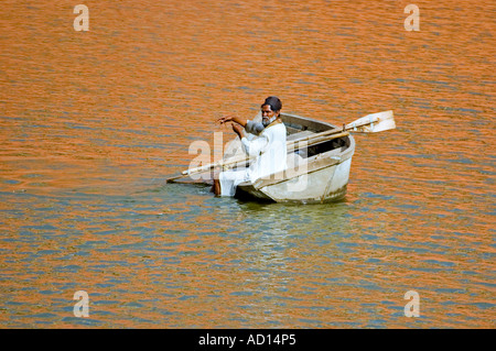 Horizontale Ansicht von einem einsamen indische Fischer Angeln im Maota-See mit orangefarbenen Reflexen von Amber Palast auf dem Wasser. Stockfoto