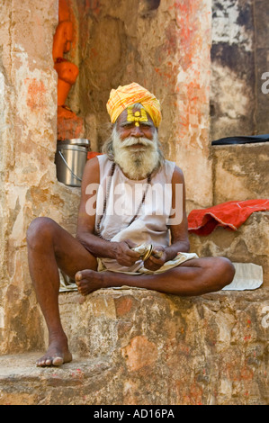 Vertikale Bildniss eines älteren Sadhu trägt mit einer leuchtend gelben Turban und bemalten Facesitting auf Stufen Jehangir Palace Stockfoto