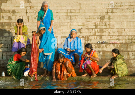 Horizontale Porträt einer Gruppe von indischen Frauen in traditionellen Saris waschen an den Ghats entlang dem Fluss Ganges. Stockfoto