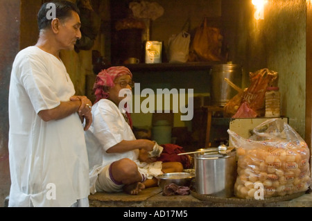 Horizontale Porträt eines indische Fastfood-Chef für einen Kunden mit tiefer gebratene gefüllte Puri Kugeln frisch in seinem Geschäft. Stockfoto