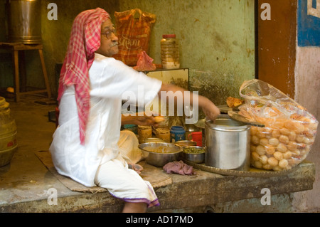 Horizontale Porträt ein indisches Fastfood-Koch dal auf einen Schritt vor seinen laden kleine tiefe gebratenen Puris Kugeln einfüllen. Stockfoto