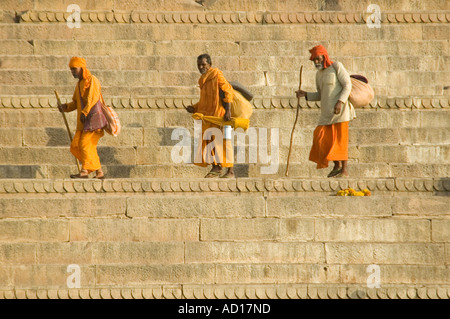 Horizontale Ansicht der drei orange Sadhus in traditionellen orange Kleidung entlang Dasashvamedha Ghat am Ufer des Flusses Ganges. Stockfoto