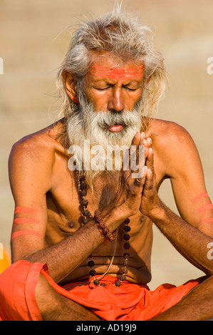 Portrait einer älteren grauen Haaren Pilger Schneidersitz sitzen im Gebet oder Meditation in einem Ghat in Varanasi. Stockfoto