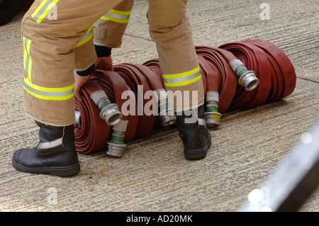 Ein Feuerwehrmann bereitet Feuerwehrschläuche aufgerollt bereit für den Einsatz. Bild von Jim Holden. Stockfoto