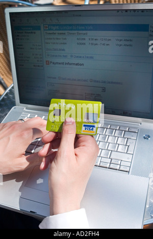 Junger Geschäftsmann macht die Zahlung auf seinem Laptop Kreditkarte außerhalb in der City of London festhalten Stockfoto