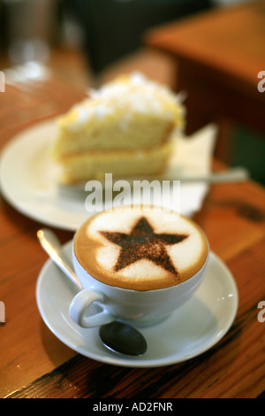 Einen Cappuccino Kaffee mit dekorativen Schokolade Stern am oberen Kolibri-Kuchen im Hintergrund Stockfoto
