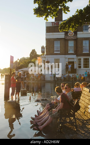 Fluss Themse in Richmond, White Cross Pub, Water Lane Drawdock, Überschwemmungen, junge Leute genießen einen abendlichen Drink draußen mit ihren Füßen im Rive Stockfoto