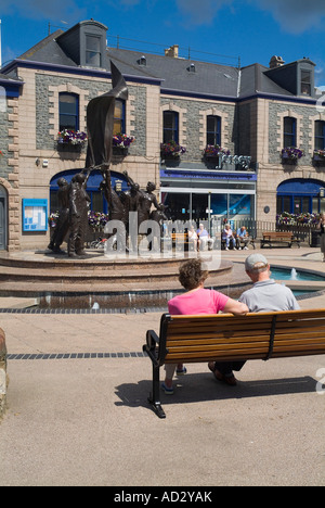 dh Liberation Square ST HELIER JERSEY Touristen Paar sitzend Liberation Statue und Jersey Tourismus Büro Gebäude Kanal Inseln war Insel Stockfoto