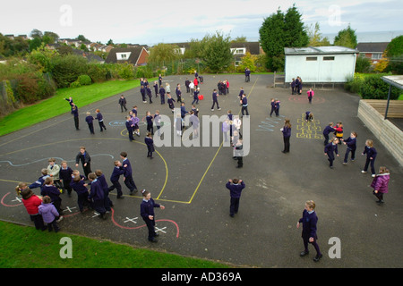 Kinder toben und spielen in den Pausen auf dem Spielplatz einer walisischen Grundschule UK Stockfoto