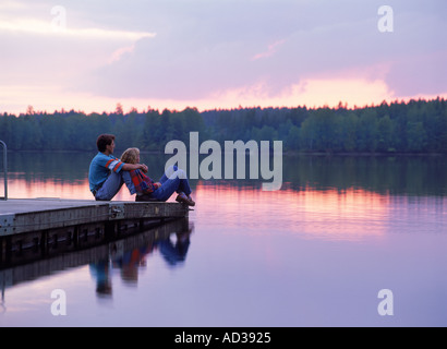 Paar am See Pier bei Sonnenuntergang Stockfoto