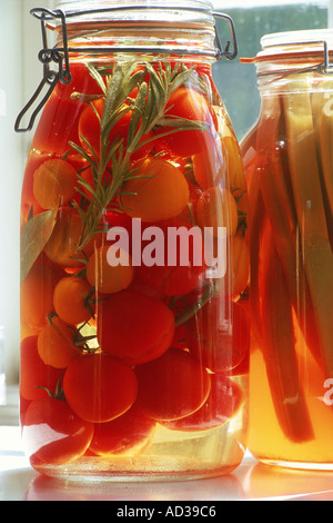 Versiegelte Gläser erhaltene rote Tomaten und Rhabarber in Flüssigkeit auf der Fensterbank Stockfoto