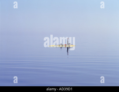 Mann und sein bester Freund allein mit Fernglas und Aktenkoffer auf winzigen Stockholmer Schären-Insel Stockfoto