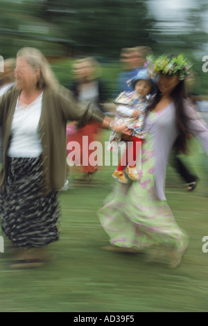 Eltern und Kinder tanzen um den Maibaum beim Mittsommerfest in Schweden Stockfoto